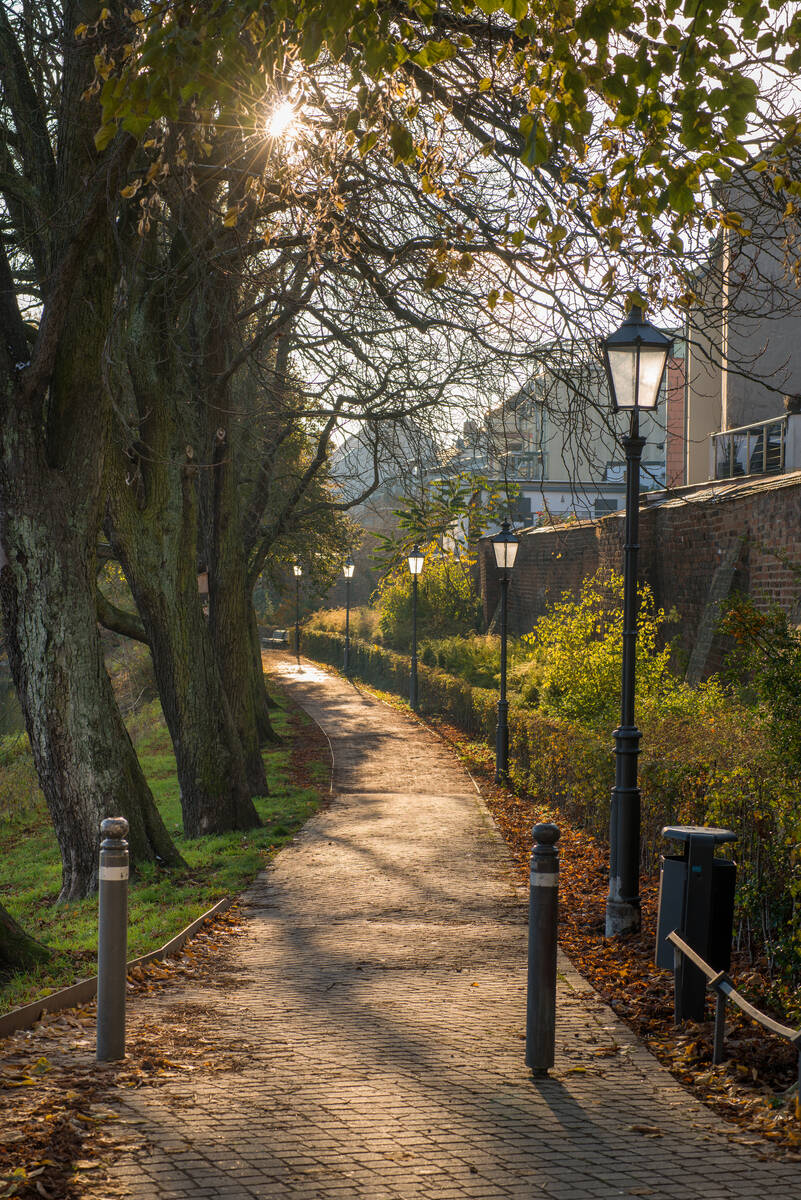 Fußweg unter klassischen Laternen entlang der Havel im Gegenlicht